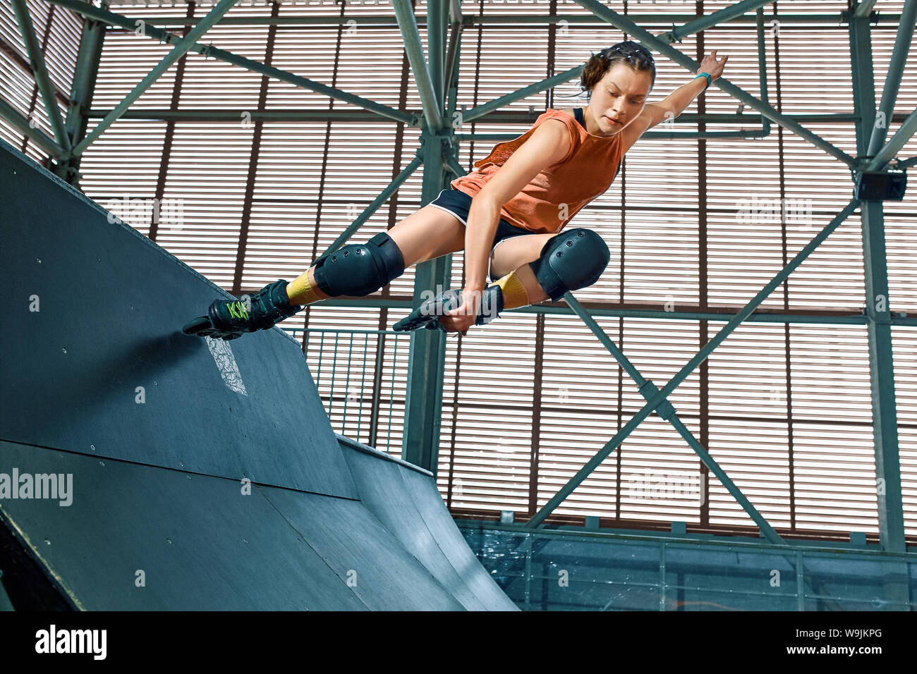 Rollerblader jump high from big air ramp performing trick. Indoors