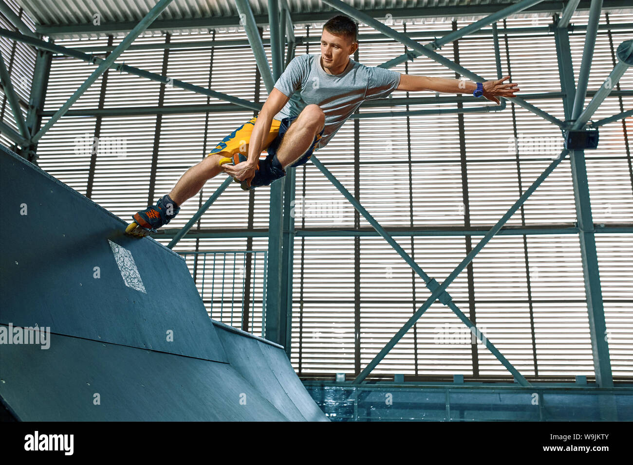 Rollerblader jump high from big air ramp performing trick. Indoors