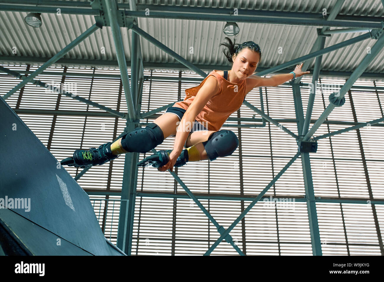 Rollerblader jump high from big air ramp performing trick. Indoors