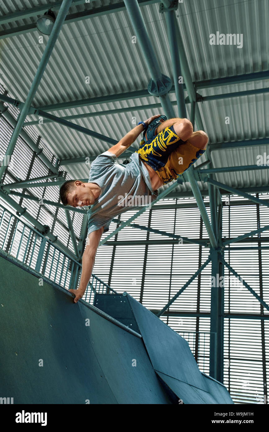 Rollerblader jump high from big air ramp performing trick. Indoors