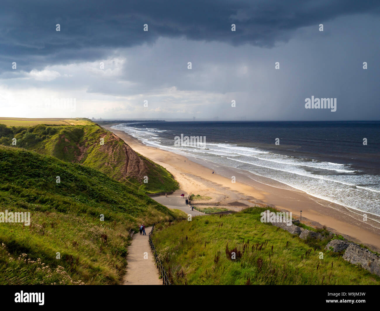 View in summer north along Saltburn Beach towards Redcar with Nimbus clouds and an approaching thunderstorm Stock Photo