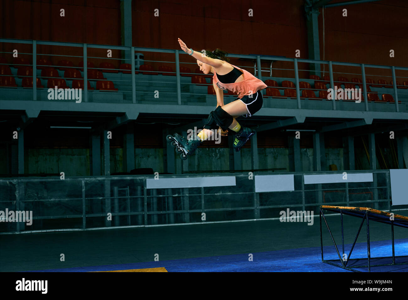 Rollerblader jump high from big air ramp performing trick. Indoors