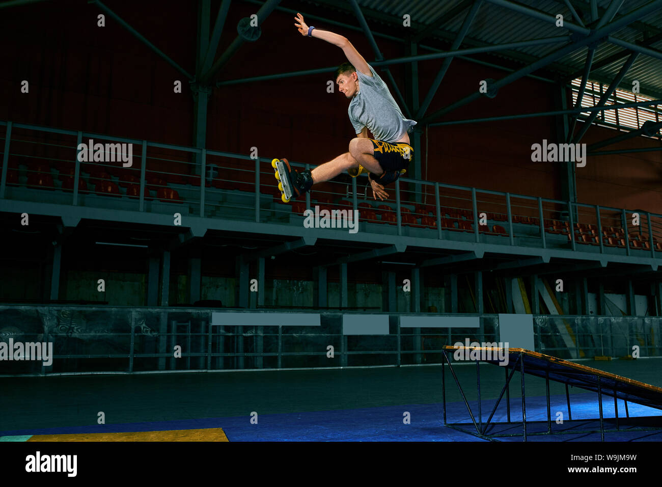 Rollerblader jump high from big air ramp performing trick. Indoors