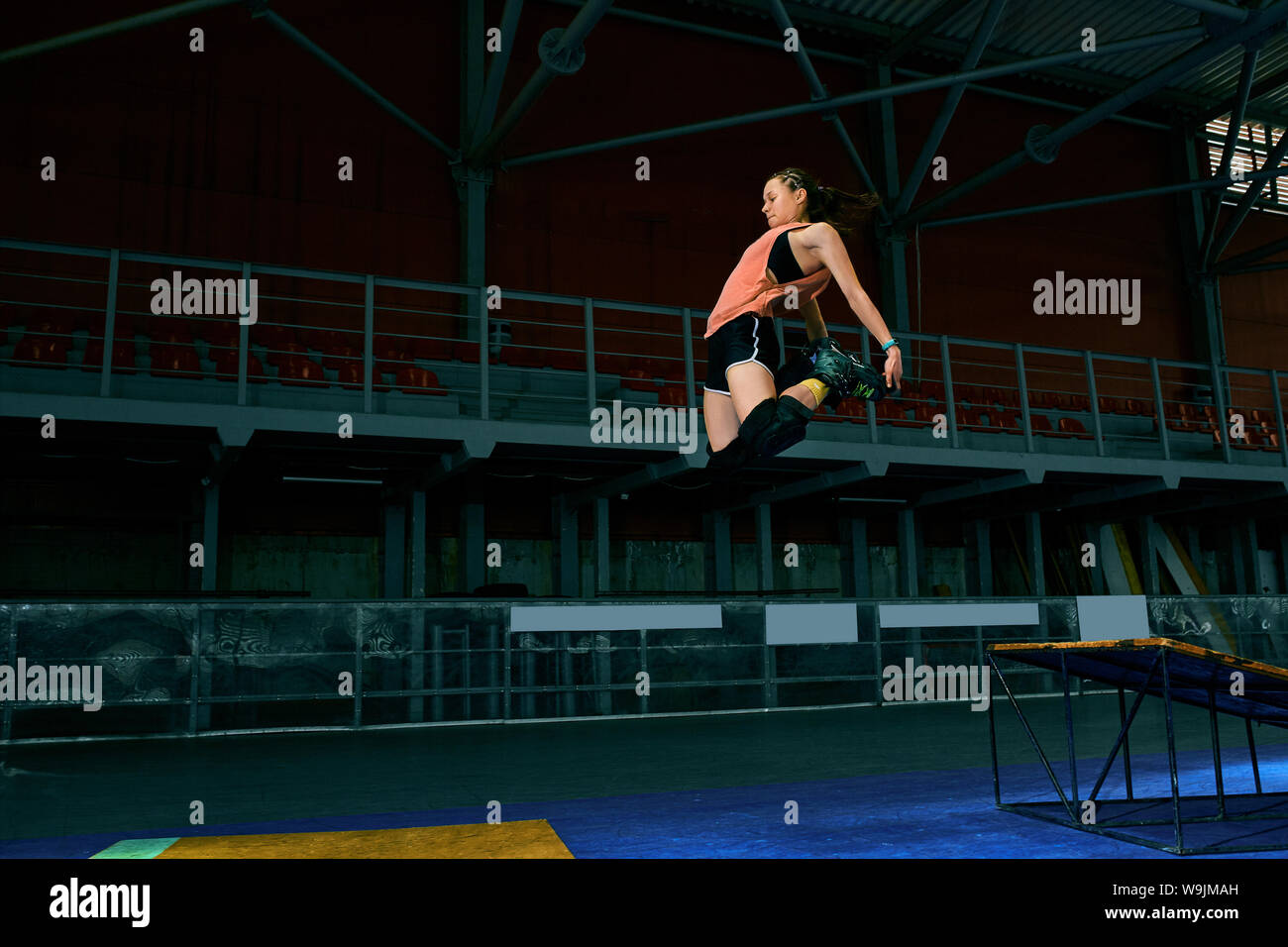 Rollerblader jump high from big air ramp performing trick. Indoors