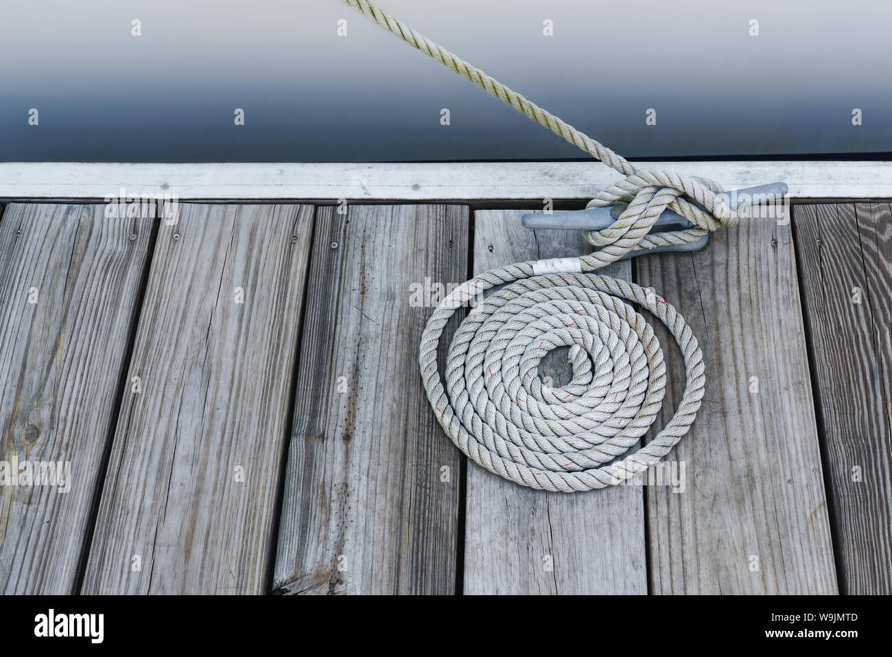 A coil of thick shipping rope on the stone floor of a shed