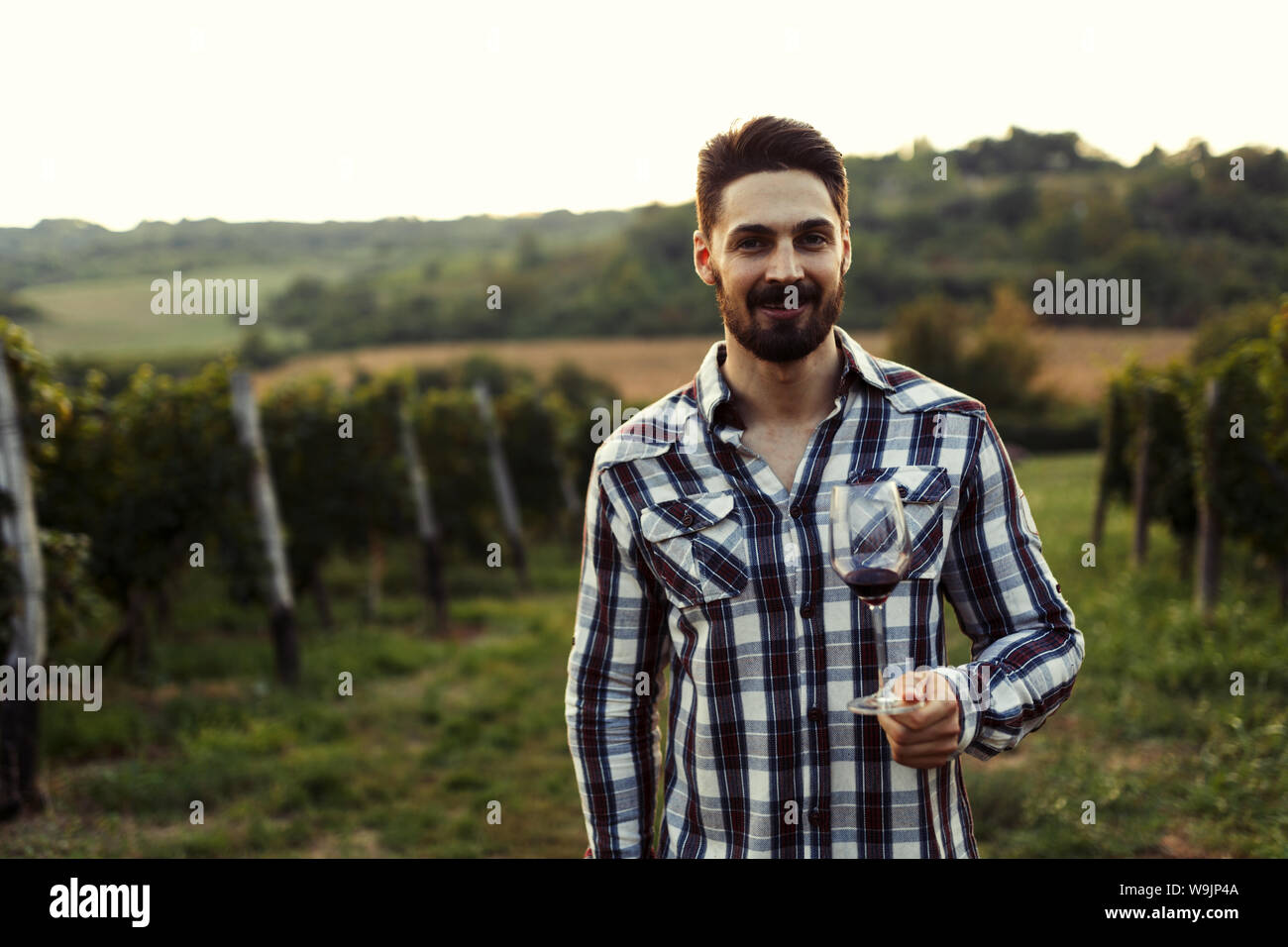 Young handsome man drinking wine in vineyard Stock Photo