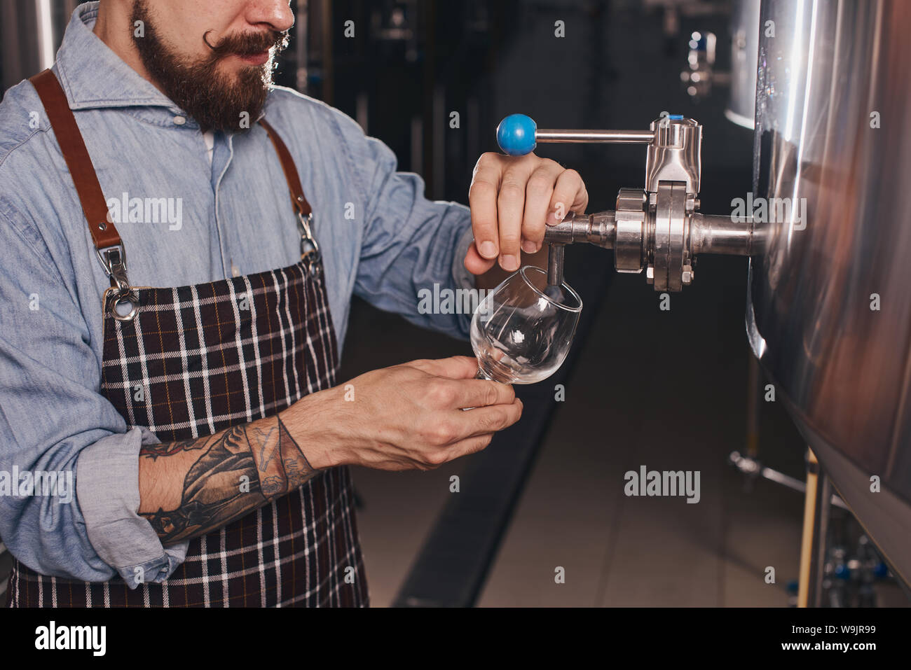 Close up of bartender at work pouring beer from the taps into clear glasses. Stock Photo