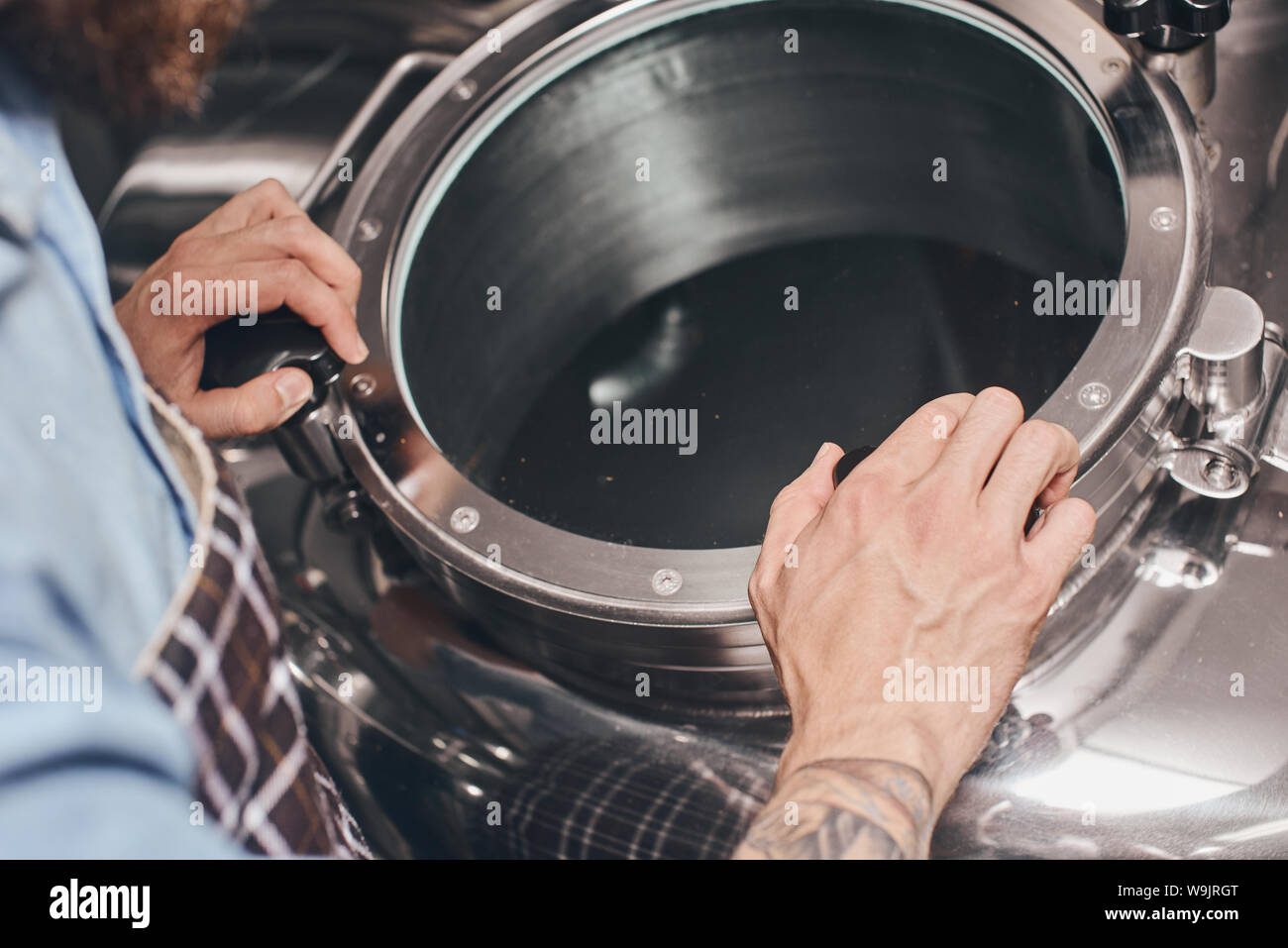 Close up of an empty beer barrel being opened by brewery worker. Stock Photo