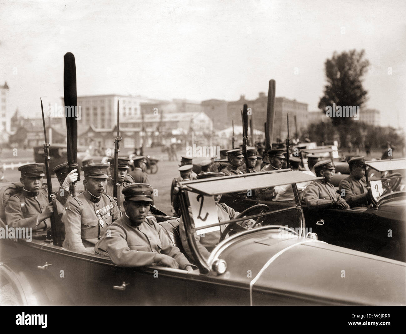 [ 1930s Japan - Japanese Soldiers in Cars ] —   Uniformed Japanese soldiers in cars hold their wrapped regimental flags. The flag bearers are flanked by soldiers holding rifles with fixed bayonets.  20th century vintage gelatin silver print. Stock Photo