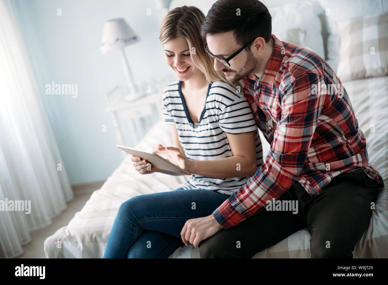 Young happy couple using tablet in bedroom Stock Photo