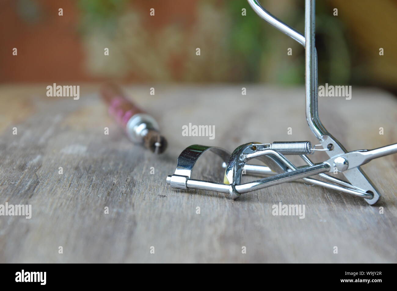 eyelash curler and mascara brush on wooden board Stock Photo