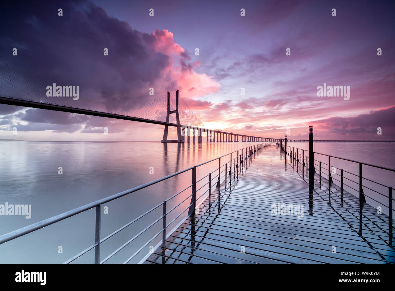 Sunrise colors the clouds reflected in Tagus River and frame the Vasco da Gama bridge in Lisbon, Portugal, Europe Stock Photo