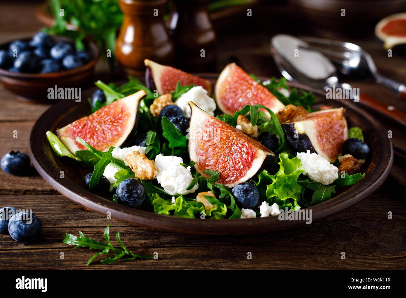 Fig salad with goat cheese, blueberry, walnuts and arugula on wooden
