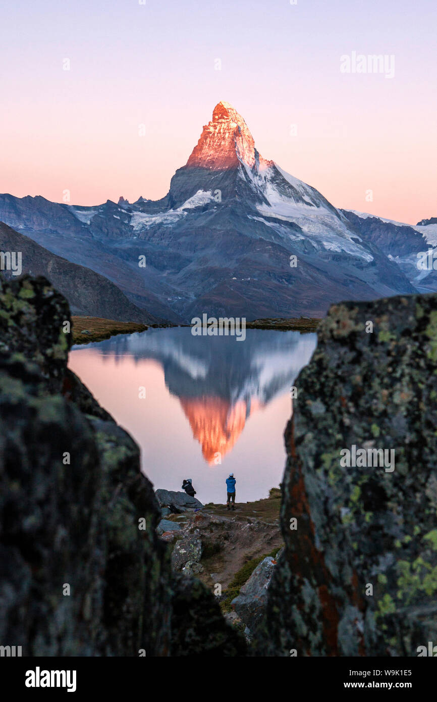 Hikers admire the Matterhorn reflected in the Stellisee at sunrise, Zermatt, Canton of Valais, Pennine Alps, Swiss Alps, Switzerland, Europe Stock Photo