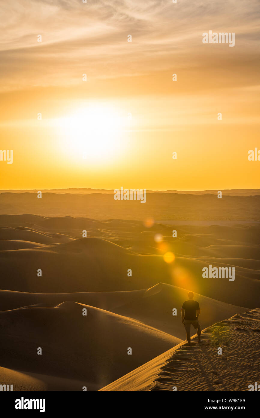 Man enjoying the sunset in the giant sand dunes of the Sahara Desert, Timimoun, western Algeria, North Africa, Africa Stock Photo