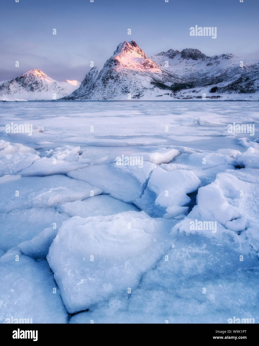 Frozen lake in front of mountain in the early morning light, Lofoten ...
