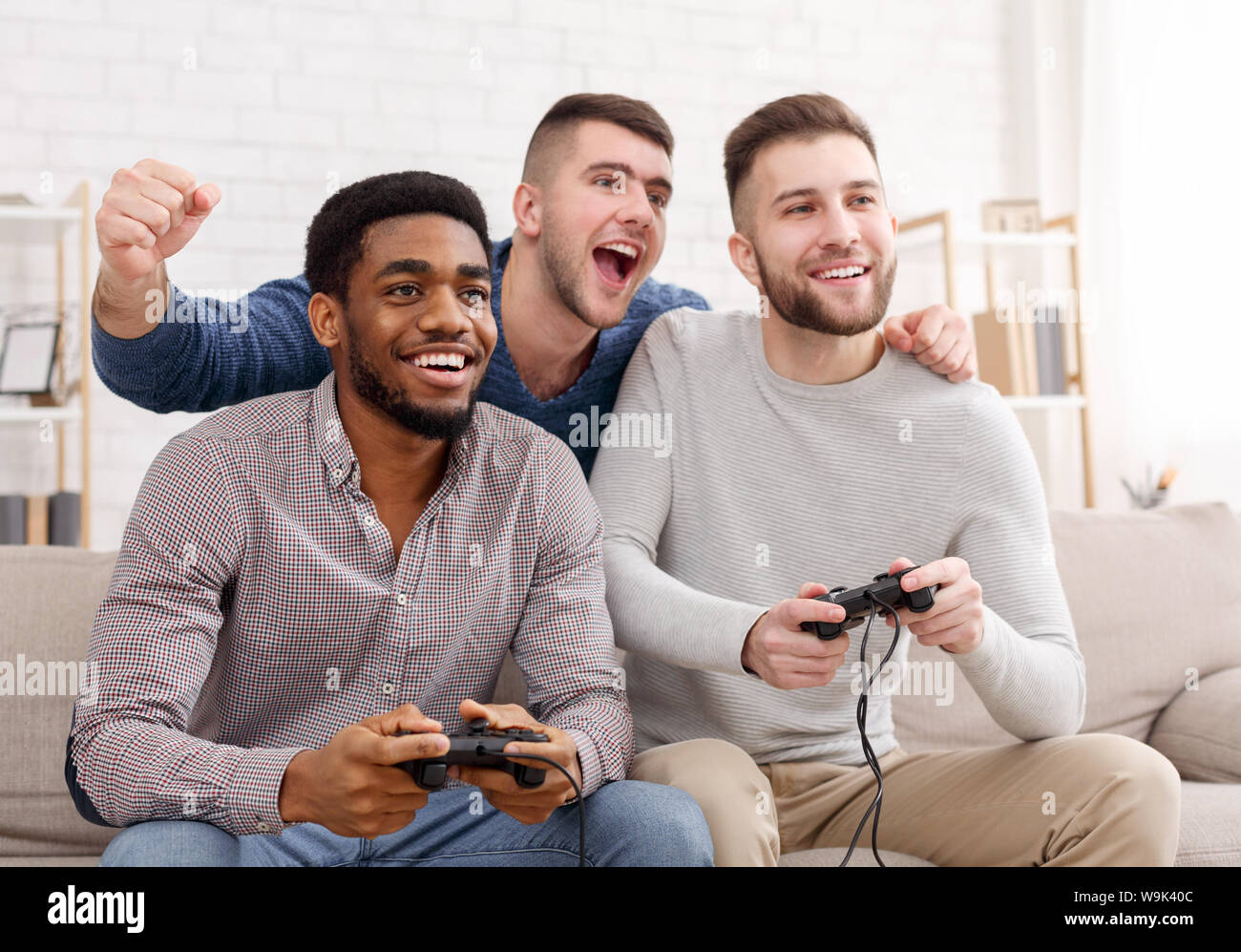 Diverse mates playing video games, holding joysticks Stock Photo