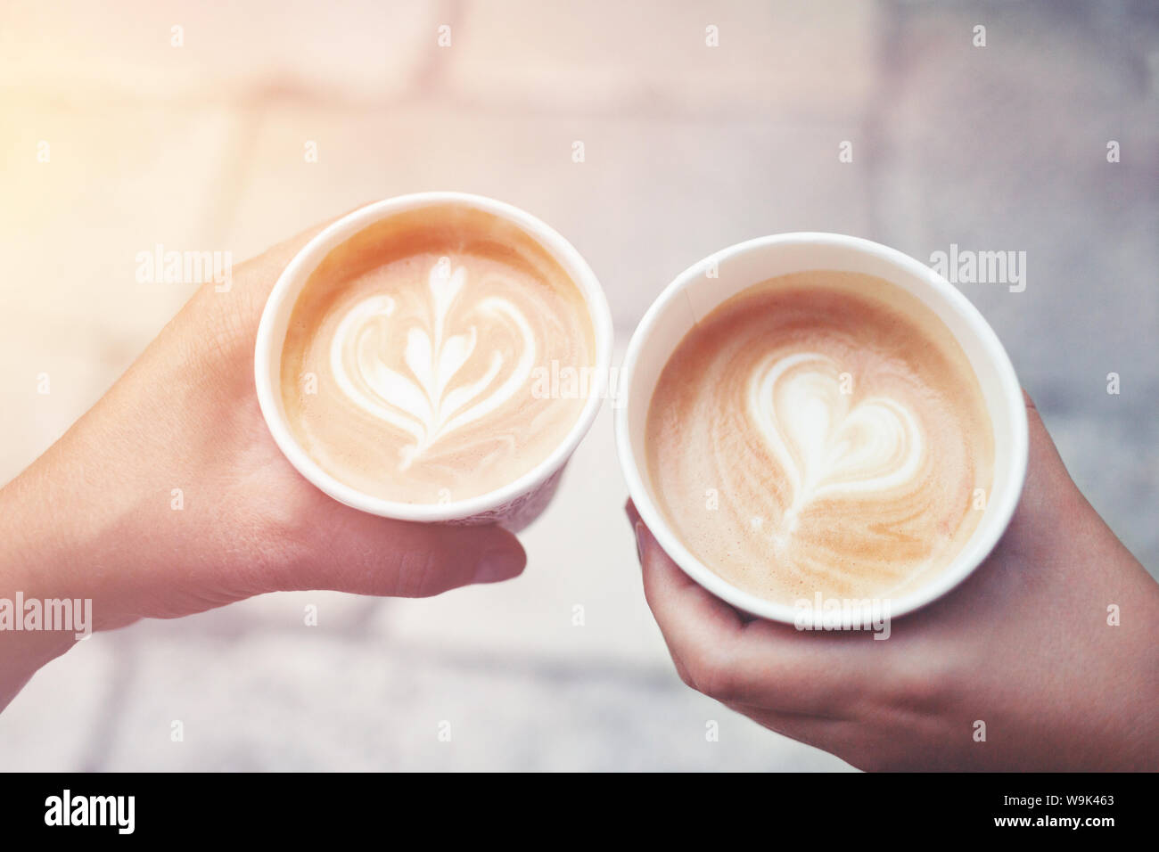 Morning take-away coffee in hands with latte art. Morning cappuccino concept. Top view. Stock Photo