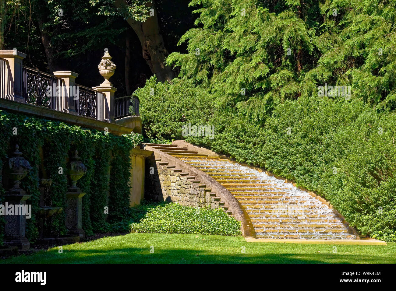 curved stone staircase; water cascading, outdoors; soothing sound; tranquil; green grass; trees; scenic; decorative railing, urns, Italian Water Garde Stock Photo