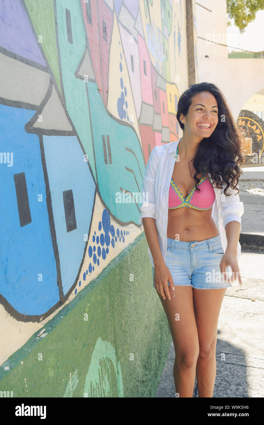 Young Brazilian woman happy and smiling next to a graffiti wall in Lapa, central Rio de Janeiro, Brazil, South America Stock Photo