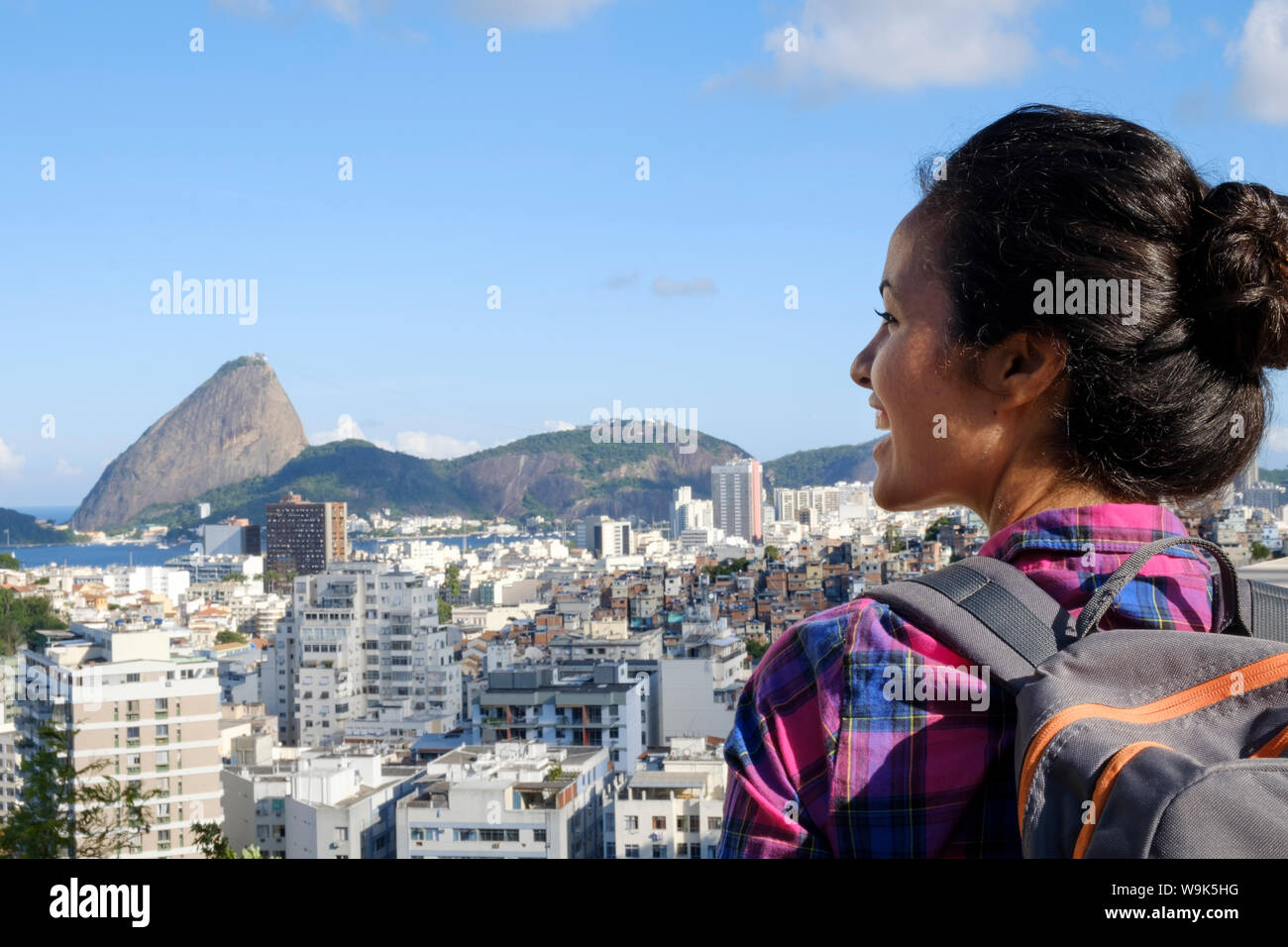 Young backpacker on her mobile phone in central Rio de Janeiro with the Sugar Loaf in the distance, Rio de Janeiro, Brazil, South America Stock Photo