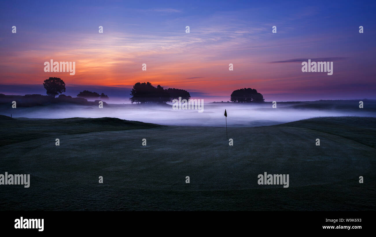 Dawn sky extending beyond the mist low lying in the sunken fairways of Delamere Forest Golf Club on a spring morning, Cheshire, England, UK Stock Photo