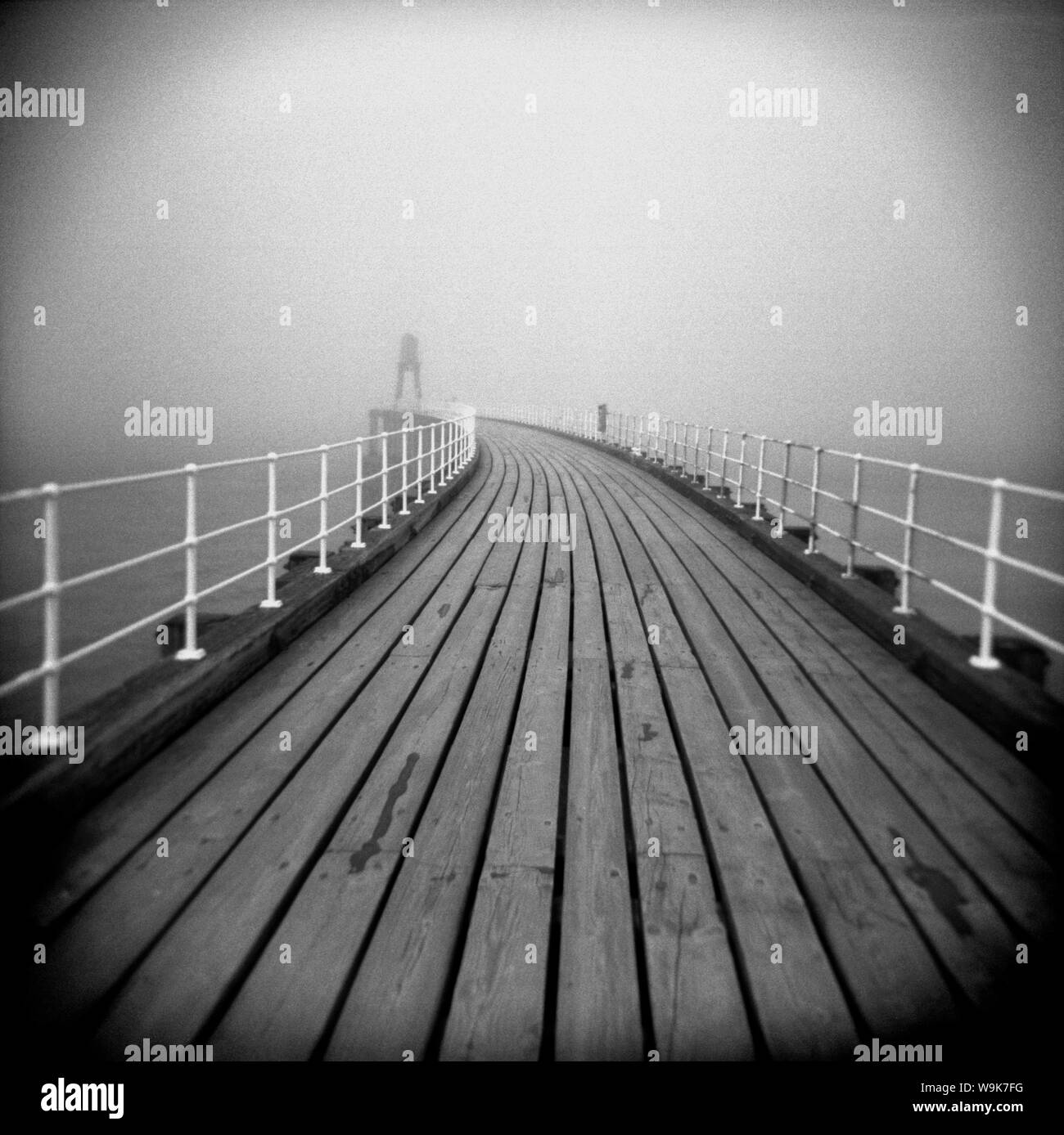 Looking along timber boardwalk of Whitby pier on misty winter's day, Whitby, North Yorkshire, England, UK Stock Photo