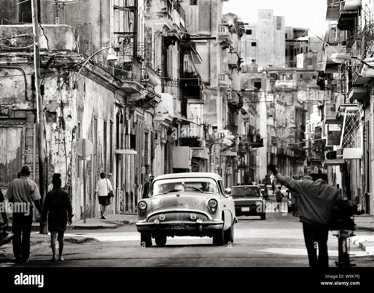 Busy street showing dilapidated buildings, old American cars and local people, Havana, Cuba, West Indies Stock Photo