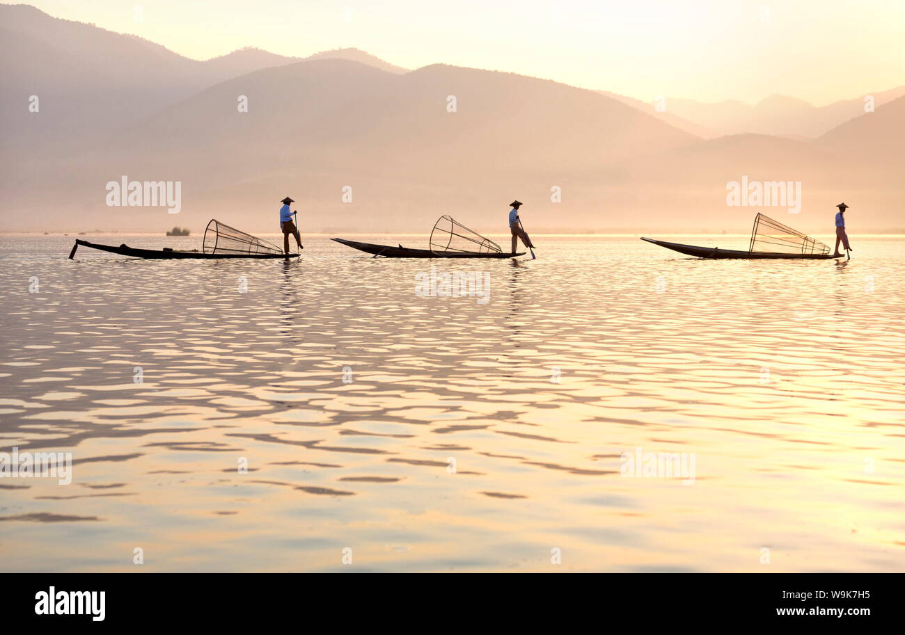 Intha 'leg rowing' fishermen at sunset on Inle Lake who fish using nets stretched over conical bamboo frames, Inle Lake, Myanmar Stock Photo