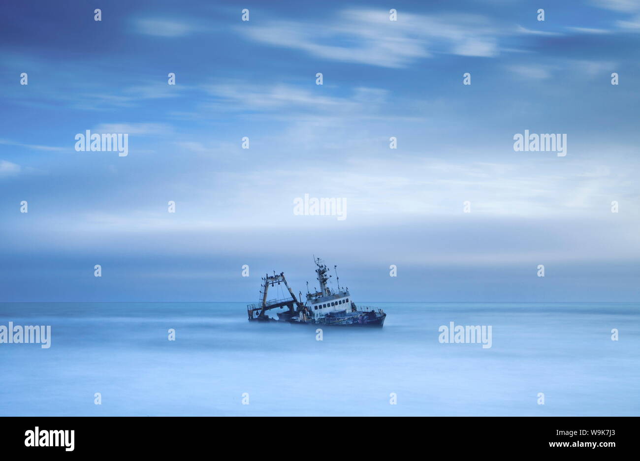 Shipwreck off the Atlantic coast, shot with long exposure to record motion in sea and sky, near Walvis Bay, Namibia, Africa Stock Photo