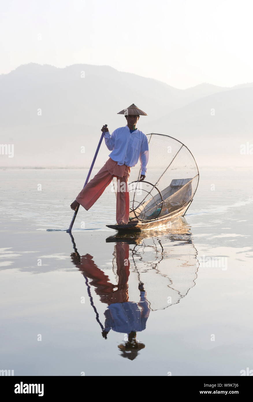 Intha 'leg rowing' fishermen at sunset on Inle Lake who fish using nets stretched over conical bamboo frames, Inle Lake, Myanmar Stock Photo
