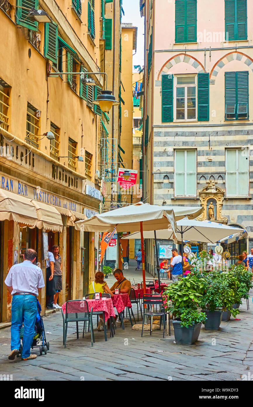 Genoa, Italy - July 06, 2019: Old street in Genoa and people in cafe Stock Photo