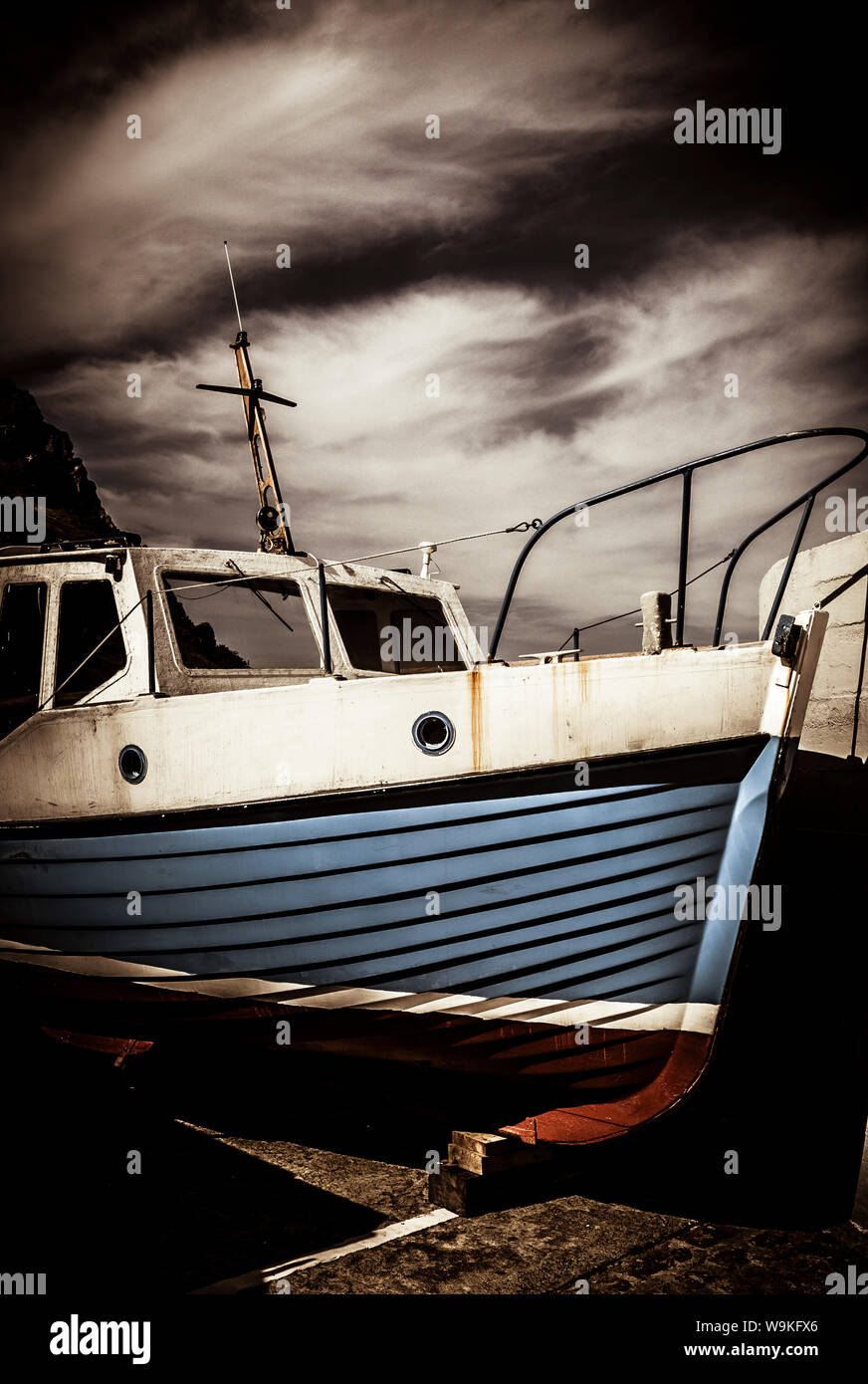 small fishing boat out of water against a stormy sky Stock Photo