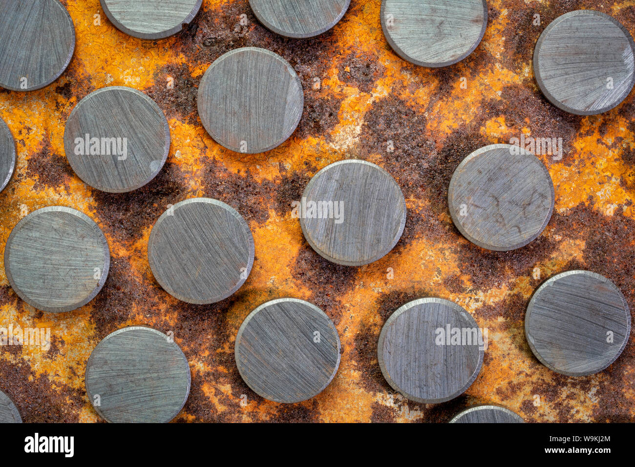 set of small round ceramic ferrite magnets - top view against rusty metal sheet Stock Photo