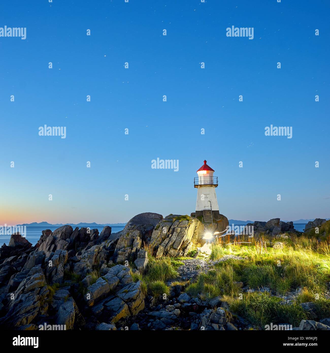 A magical moment in Norway. I found this lighthouse in Lofoten. A family is running into my picture. Stock Photo