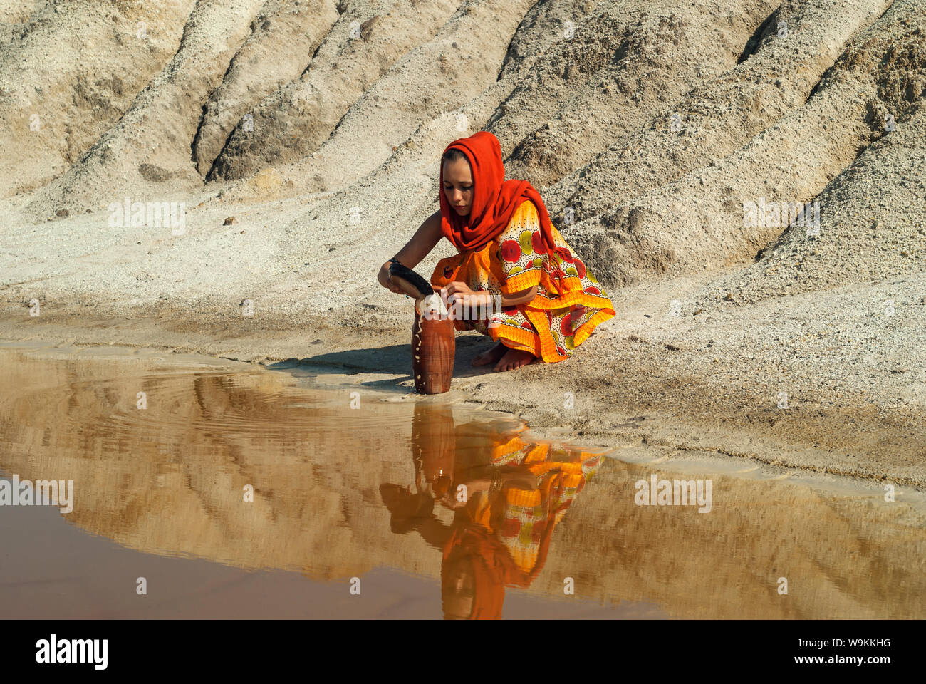 girl of oriental appearance in sari and hijab fills the pitcher with water  from a dirty source in the arid area Stock Photo - Alamy