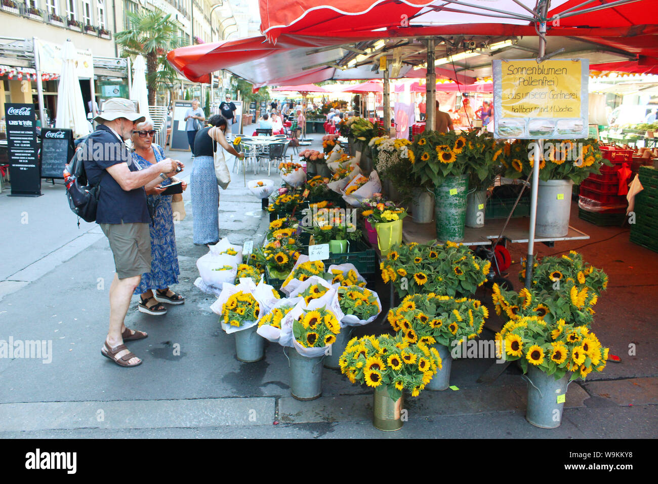 Bern, Switzerland - July 23, 2019: Visitors looking at, and photographing  sunflowers at the marketplace in Bern near the street Bärenplatz Stock Photo