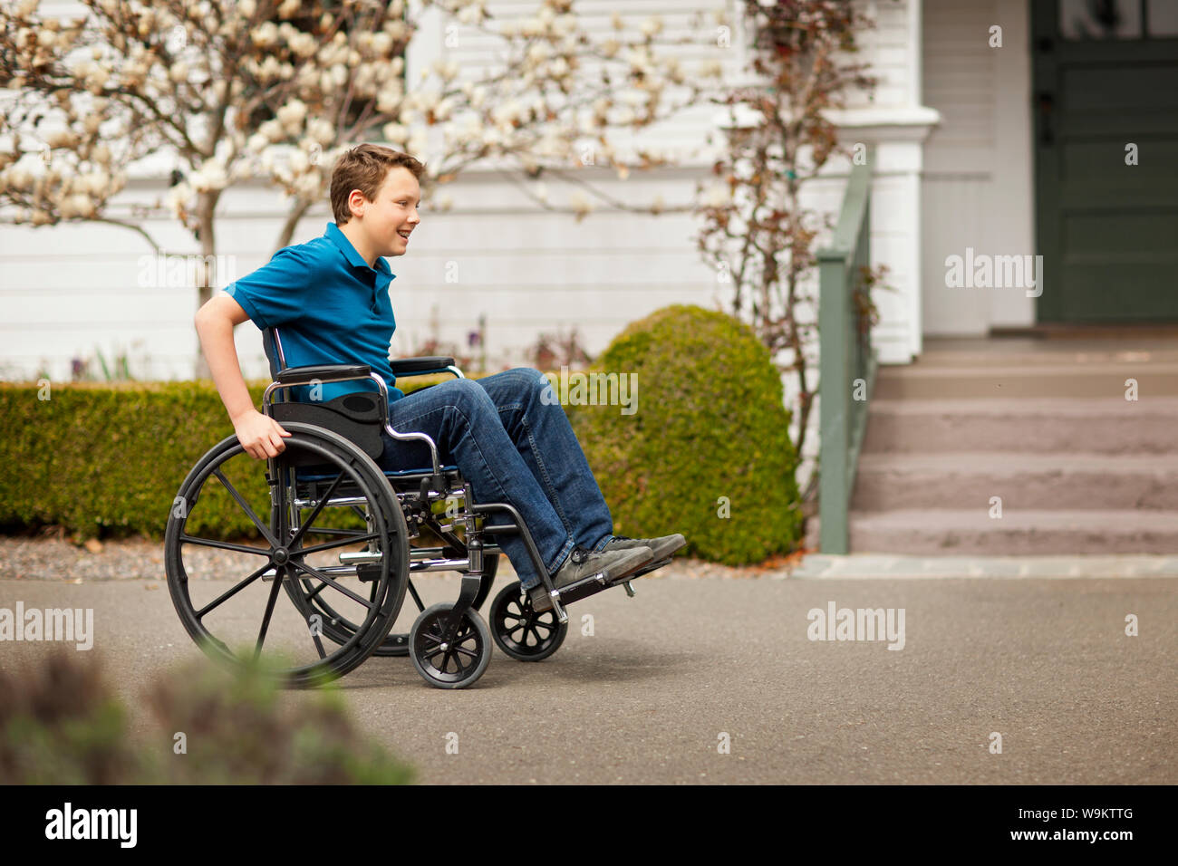 Teenage boy pushing himself in a wheelchair Stock Photo - Alamy