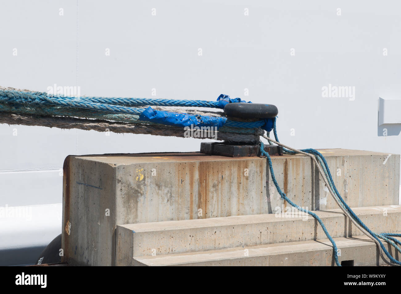Thick mooring rope teathered to mooring post on harbour dock Stock