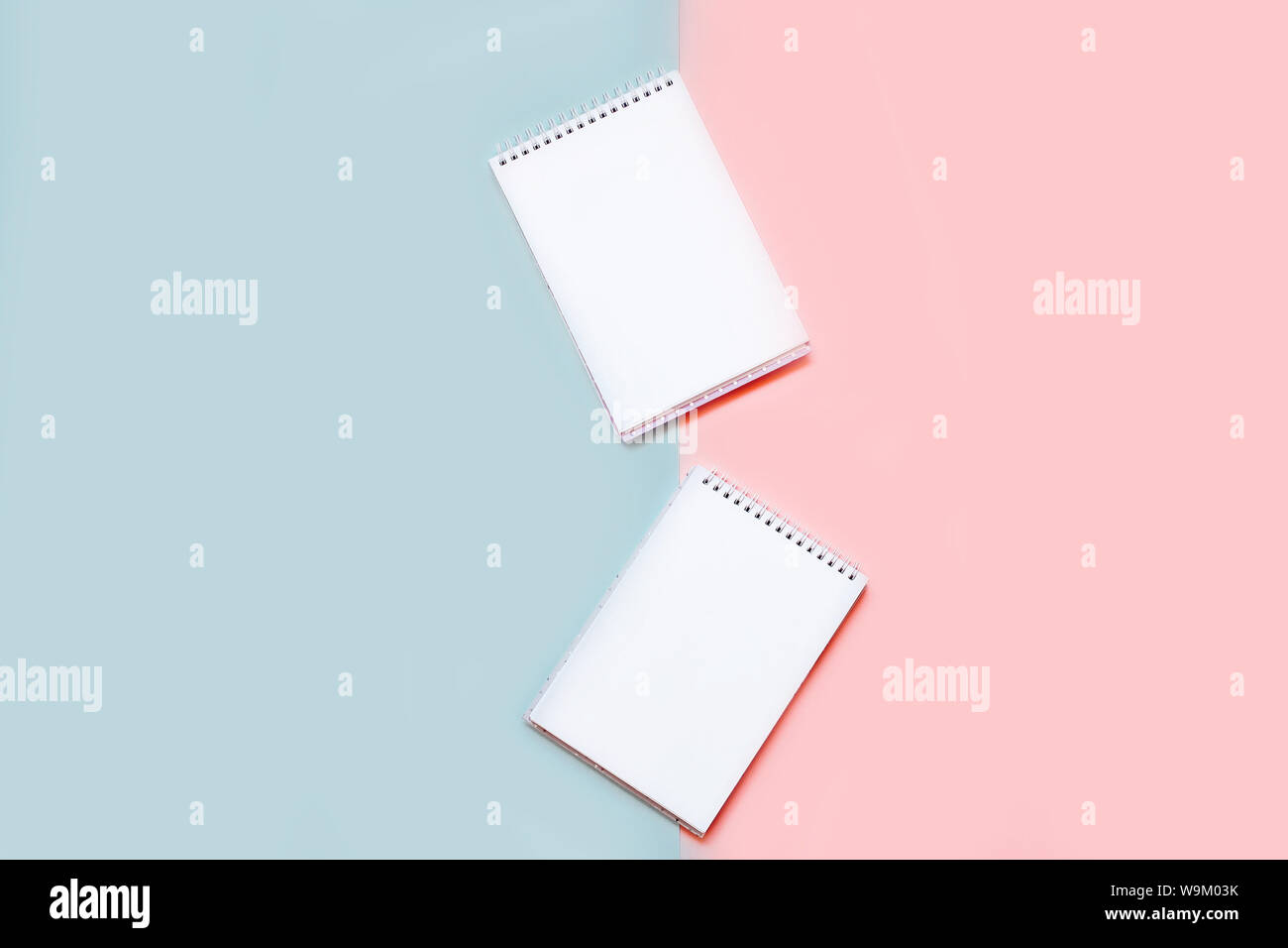 Two notebooks with blank white sheets on a pink and blue background Stock Photo