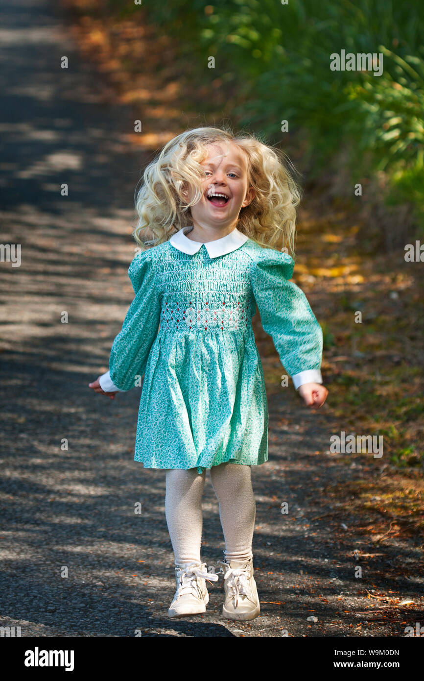 A young toddler blonde girl jumping for joy Stock Photo