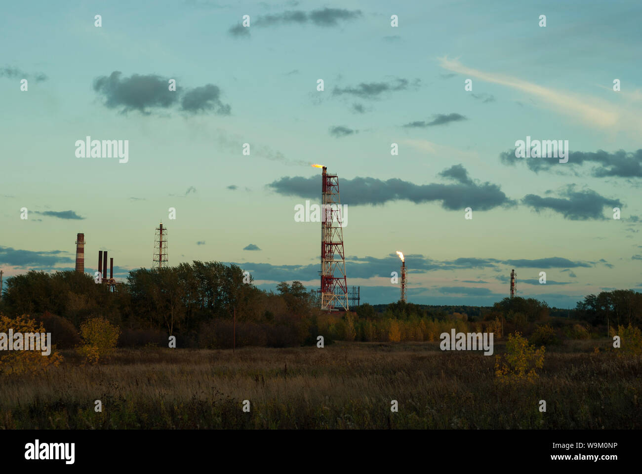 evening industrial landscape - flares for flaring associated gas in an oil field Stock Photo