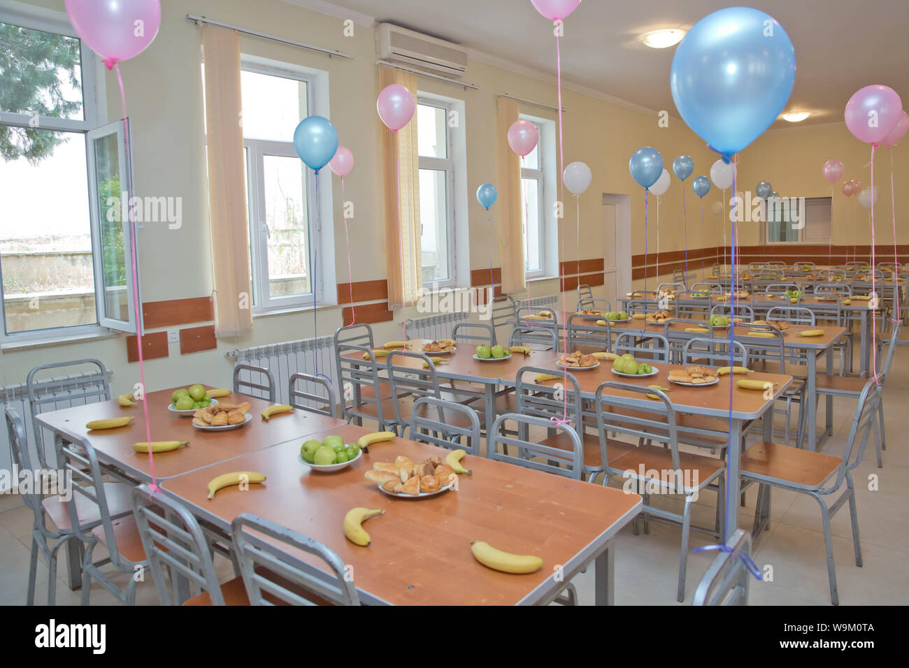 Food aid for orphans . kids eating lunch in a social school  orphanage,population are orphans,due . Blue and pink balls on the tables.  Bananas, apples Stock Photo - Alamy