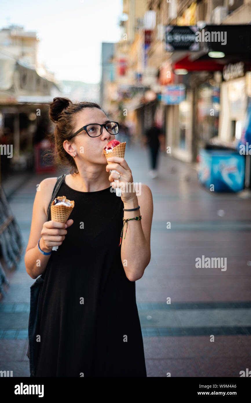 Cute hipster girl eating two ice creams on the street Stock Photo