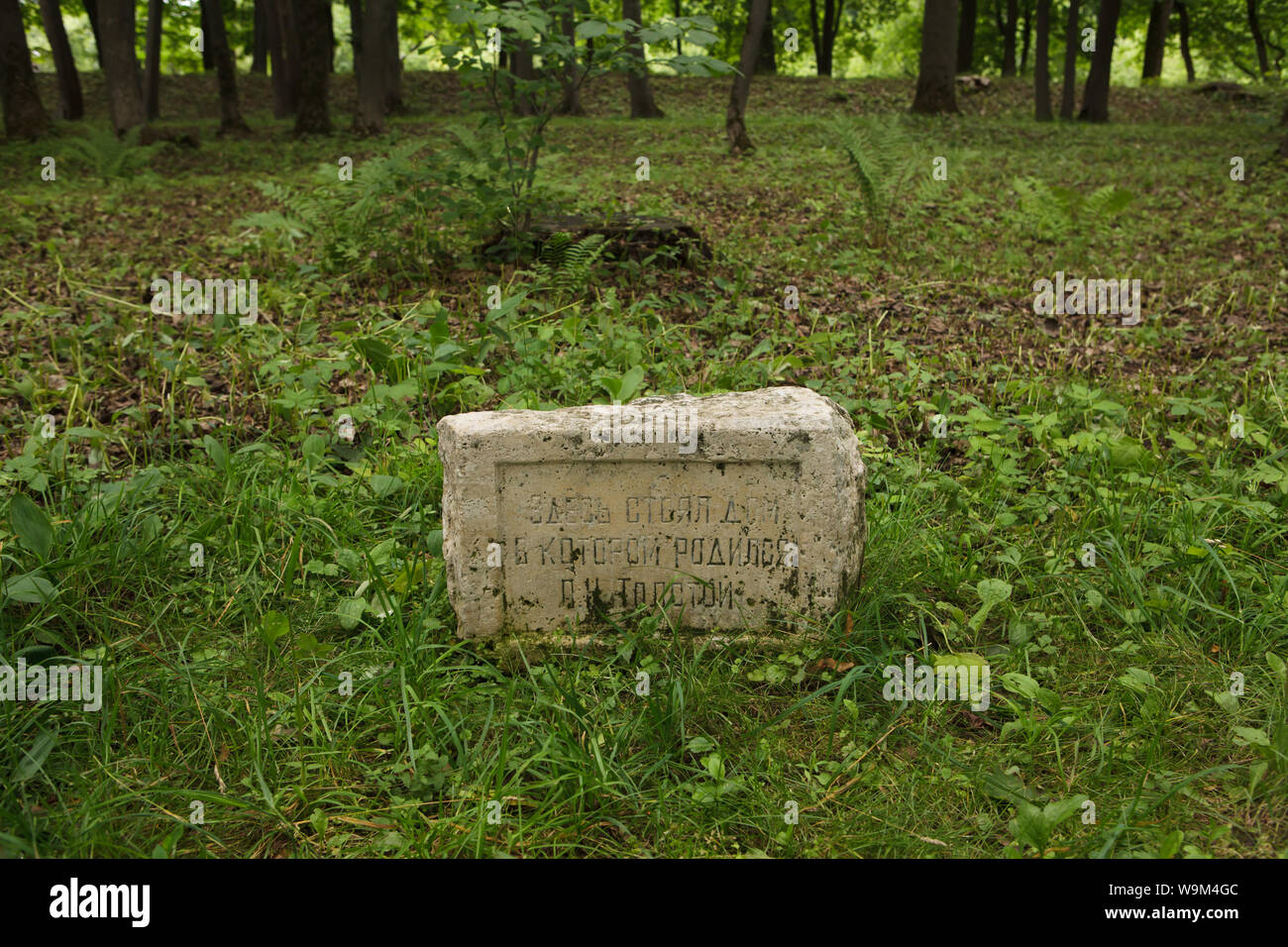 Memorial stone on the place where Russian writer Leo Tolstoy was born in the house which once stood on this place in the Leo Tolstoy memorial estate in Yasnaya Polyana near Tula, Russia. Text in Russian means: The house once stood here where Leo Tolstoy was born. Stock Photo