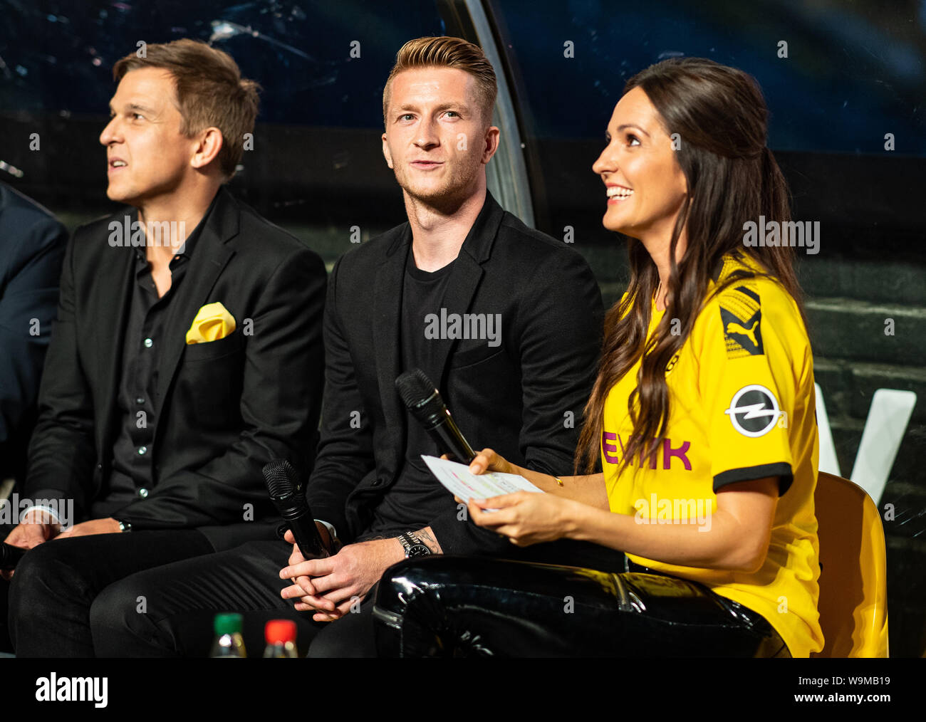 Dortmund, Germany. 14th Aug, 2019. Soccer: Bundesliga: Christoph Schneider  (l-r), Managing Director Amazon Prime Video Deutschland, Dortmund player  Marco Reus and presenter Johanna Klum sit on a bench in the stands at