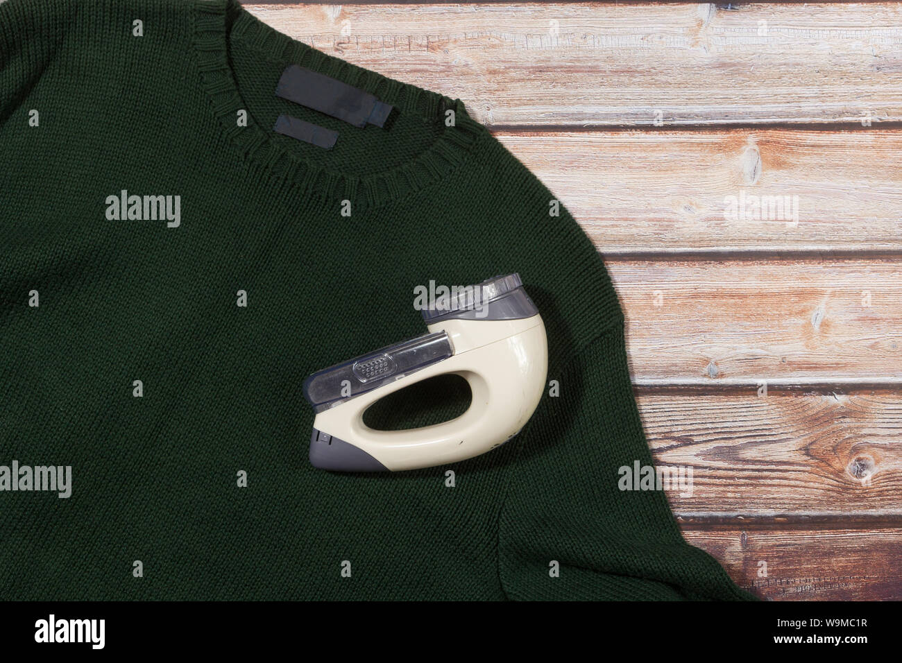 wool sweater with electric lint remover on wooden background Stock Photo