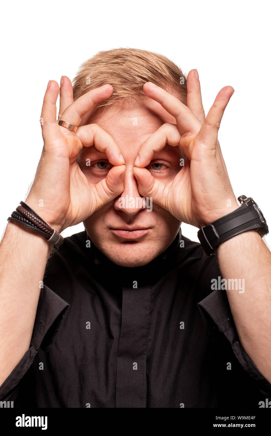 Young blond man in a black shirt, watches and bracelet is making faces, isolated on a white background Stock Photo