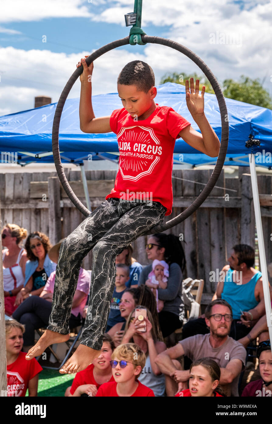 African American boy performing on circus rings hoops Lyras; Salida Circus summer camp finale; Salida; Colorado; USA Stock Photo