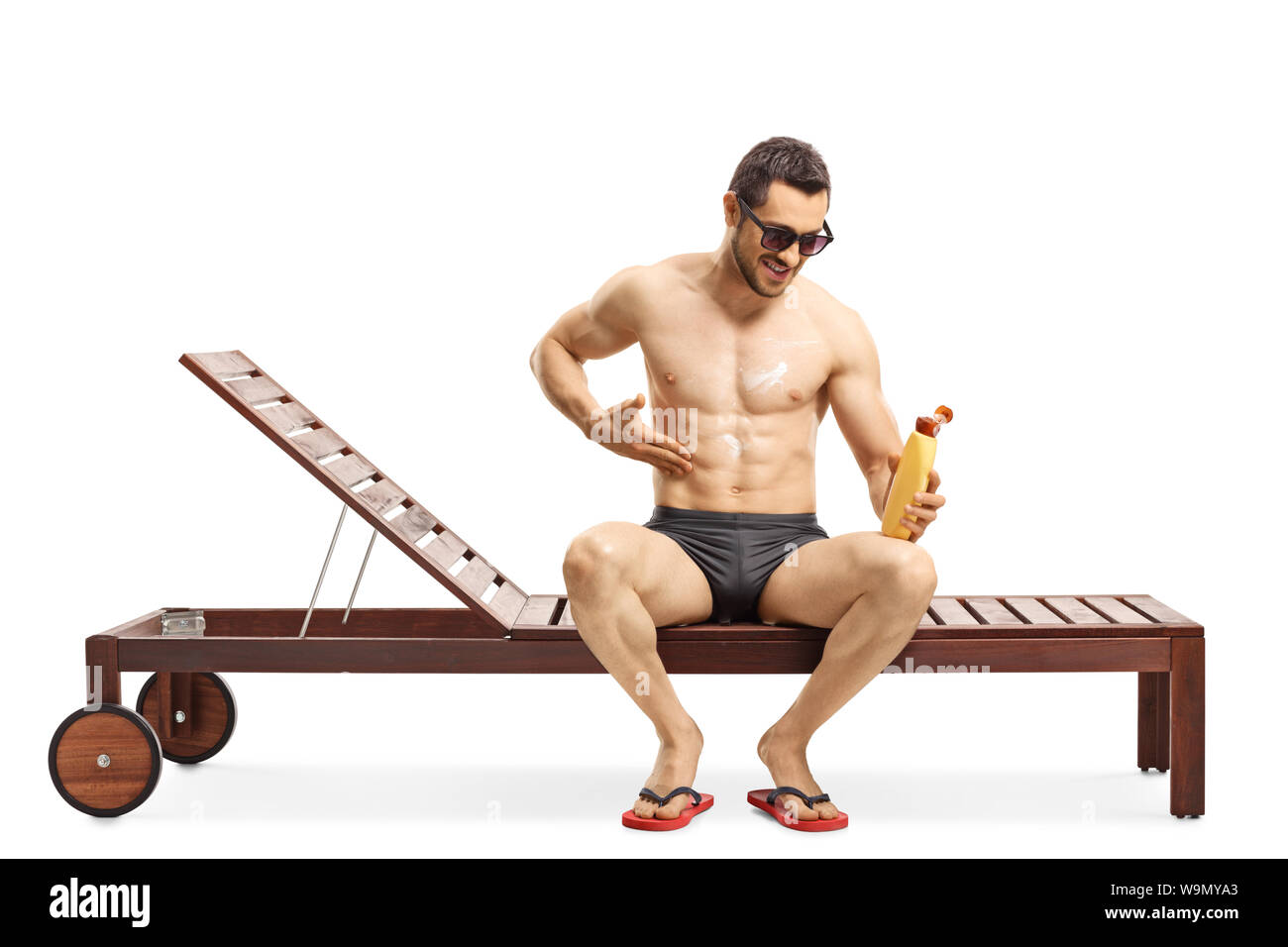 Full length shot of a young man applying sun cream and sitting on a sunbed isolated on white background Stock Photo